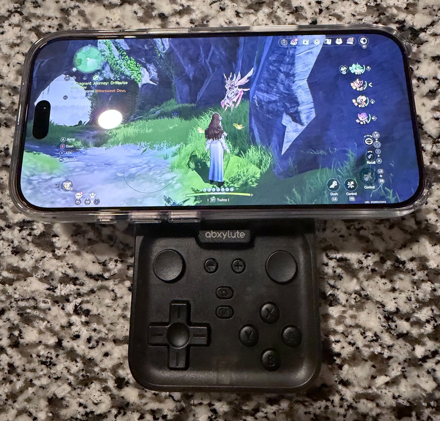 Front view of the abxylute M4 attached beneath a phone displaying Aniimo gameplay