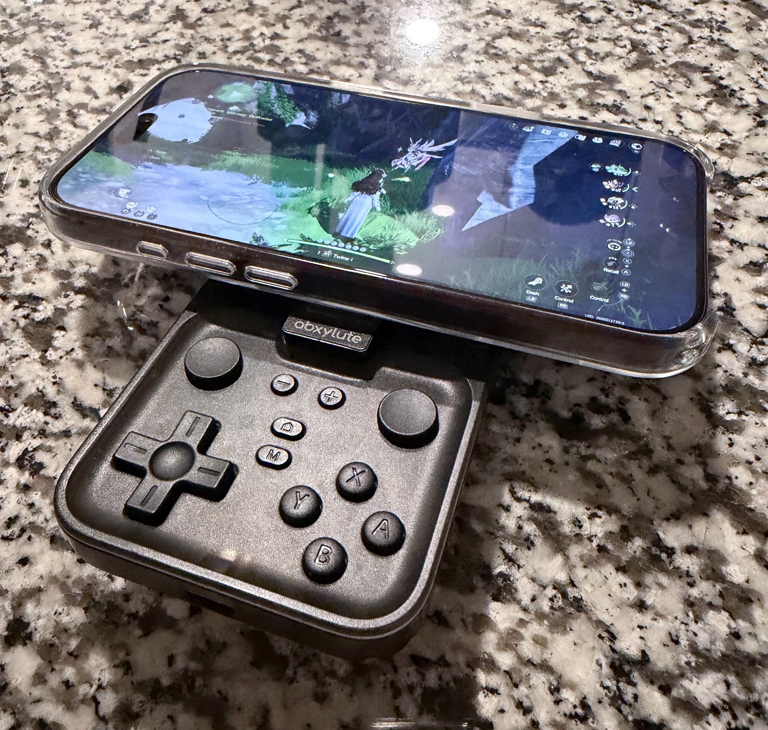 Black abxylute M4 controller attached below a phone running Aniimo